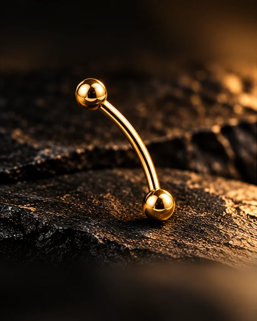 Barbell curvo dourado com duas esferas sobre ardósia escura — Sobrancelha